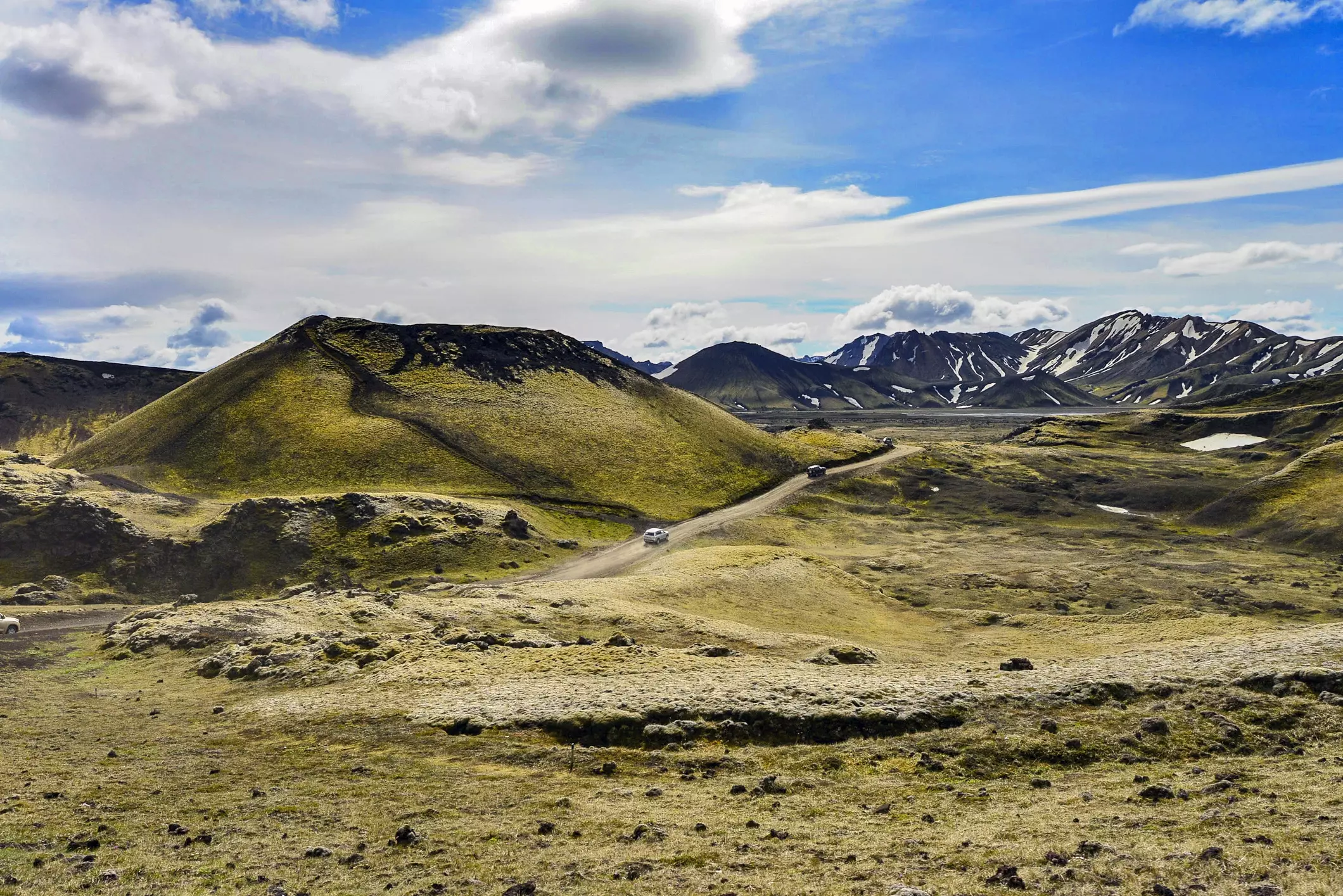 Gravel road winding between green volcanic craters in Iceland