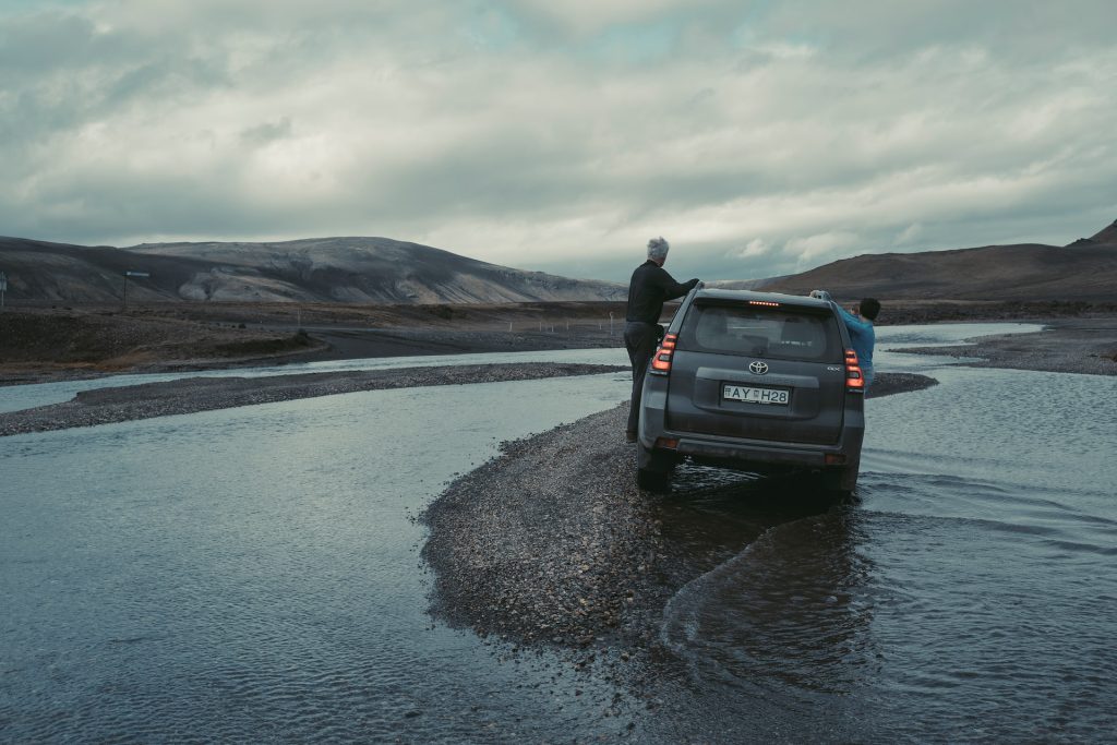 a land cruiser is crossing the river 
