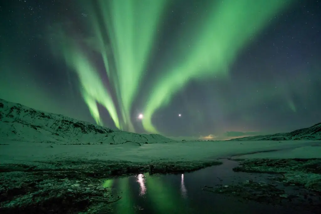 Northern Lights in Iceland with mountains covered in snow