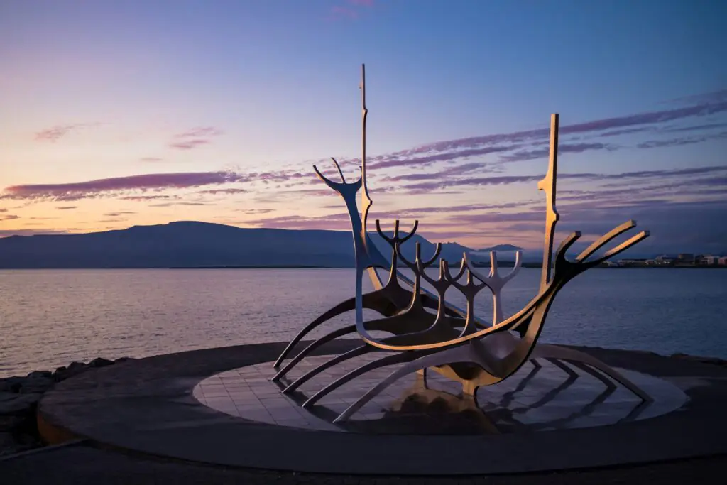 Sun Voyager Sculpture in Iceland with the ocean, mountains and midnight sun in the background.