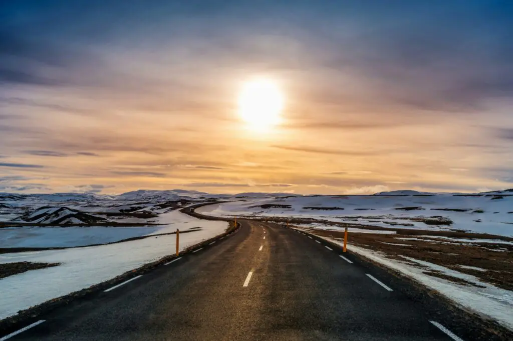 Road in Iceland with sun and snow around it
